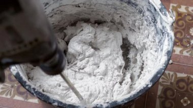 Bir insan, karışımı tamamlamak için çimento ve suyu bir kabın içine karıştırır..