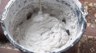 Bir insan, karışımı tamamlamak için çimento ve suyu bir kabın içine karıştırır..