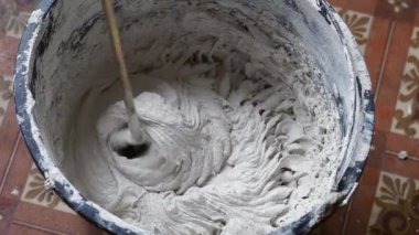 Bir insan, karışımı tamamlamak için çimento ve suyu bir kabın içine karıştırır..