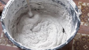 Bir insan, karışımı tamamlamak için çimento ve suyu bir kabın içine karıştırır..