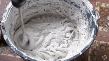 Bir insan, karışımı tamamlamak için çimento ve suyu bir kabın içine karıştırır..