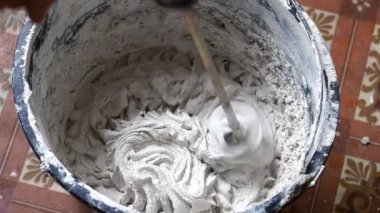 Bir insan, karışımı tamamlamak için çimento ve suyu bir kabın içine karıştırır..