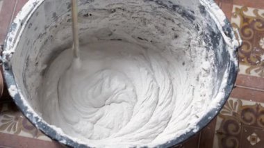 Bir insan, karışımı tamamlamak için çimento ve suyu bir kabın içine karıştırır..