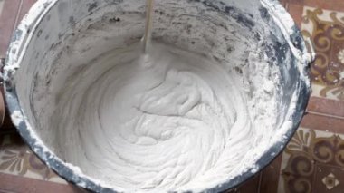 Bir insan, karışımı tamamlamak için çimento ve suyu bir kabın içine karıştırır..