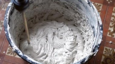 Bir insan, karışımı tamamlamak için çimento ve suyu bir kabın içine karıştırır..