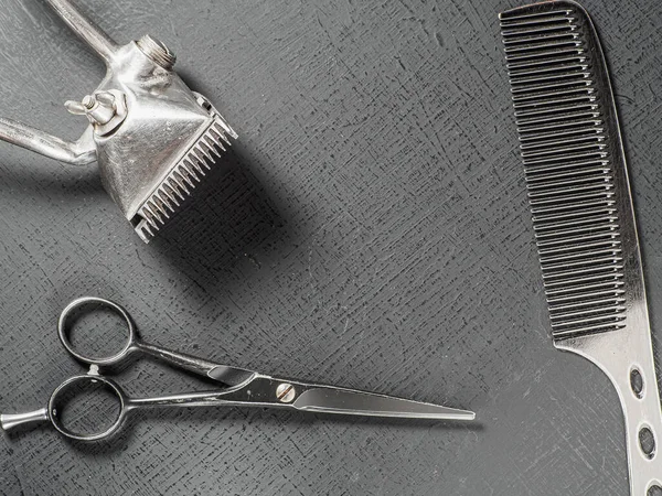 Vintage hairdressing tools. Barber scissors old manual hair clipper. On a black surface
