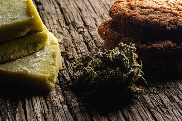 Kekse mit Marihuana und Cannabisbutter und Knospe auf altem Holzgrund in Großaufnahme. Gesunde medizinische Ernährung mit Cannabis. die Knospen sind ungenau verstreut. Rustikal. Horizontal. — Stockfoto