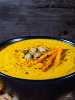 Kabak, havuç ve nohut kremalı çorba kırsal ahşap masada. Körili sonbahar balkabağı kremalı çorbası. Dikey yönelim.
