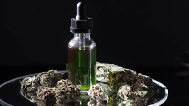 在干枯的大麻芽和医用大麻旁边 有一小瓶大麻精华素Cbd 黑暗的背景在镜子桌子上纺纱 — 图库视频影像