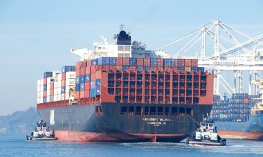 Oakland, CA - 10 Ocak 2022: APL kargo gemisi Başkan Wilson 'ın Oakland Limanı' na manevra yapmasına yardımcı olan birden fazla römorkör.