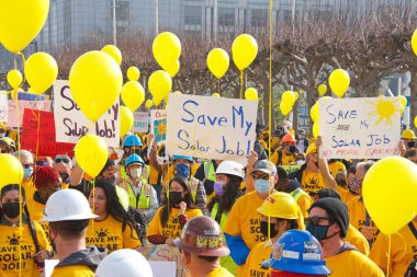 San Francisco, CA - 13 Ocak 2022: Kaliforniya 'da güneş enerjisinden tasarruf etmek için düzenlenen mitingde kimliği belirsiz katılımcılar. Tabela tutuyor, protesto için devlet binasına yürüyor..