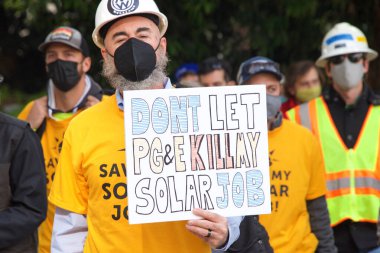 San Francisco, CA - 13 Ocak 2022: Kaliforniya 'da güneş enerjisinden tasarruf etmek için düzenlenen mitingde kimliği belirsiz katılımcılar. Tabela tutuyor, protesto için devlet binasına yürüyor..