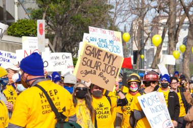 San Francisco, CA - 13 Ocak 2022: Kaliforniya 'da güneş enerjisinden tasarruf etmek için düzenlenen mitingde kimliği belirsiz katılımcılar. Tabela tutuyor, protesto için devlet binasına yürüyor..