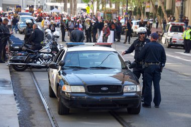 San Francisco, CA - 1 Mayıs 2022: Uluslararası İşçi Bayramı olarak da bilinen Pazar Caddesi 'nde yürüyen kimliği belirsiz katılımcılar olarak SFPD polisleri beklemede. 