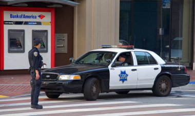 San Francisco, CA - 1 Mayıs 2022: Uluslararası İşçi Bayramı olarak da bilinen Pazar Caddesi 'nde yürüyen kimliği belirsiz katılımcılar olarak SFPD polisleri beklemede. 