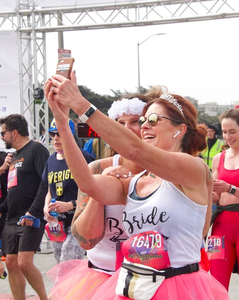 San Francisco, CA - 15 Mayıs 2022: Great Hwy 'deki yıllık Bay to Breakers yarışına katılanlar bitiş çizgisinde selfie çekiyorlar. Bay to Breakers, eğlenceli kostümler giyen birçok katılımcısıyla ünlüdür..