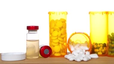 Yüksek çözünürlüklü video ilaç şişelerinin üzerinde duruyor ve yanında şırınga şişeleri ile ahşap bir masaya dökülüyor. Çoklu ilaçlar, bunaltıcı, bağımlılık, ağrı kesici.