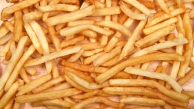 Yüksek çözünürlüklü video, arka planda hafif ahşap bir masada taze patates kızartması var. Büyük ölçüde Amerikan fast food zincirleri tarafından popüler hale getirildi..