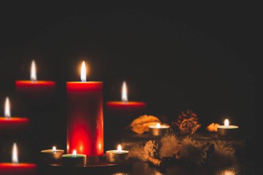 Karanlıkta sönmüş ışıklara karşı ateşli kırmızı mum ve karanlıkta altın bokeh.