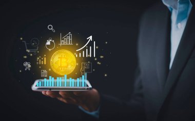 Bitcoin konsepti yığınları arasında ekranda Bitcoin grafiği olan akıllı telefon. İşadamı, hisse senedi piyasası, kripto para ve finans üzerinde büyük satın alma ve satış düğmeleri ile mobil uygulama ekranına dokundu.