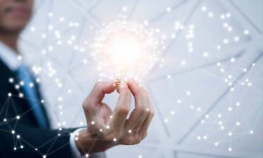 Ampulü çizgi ile tutan ve masada çalışan Adam, yaratıcılık ve yenilik başarının anahtarıdır. Enerji ve güçle yeni fikir ve yenilik kavramı, evde çalışma,