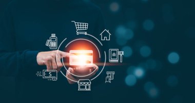İş adamı akıllı telefonu elinde tutuyor ve kredi kartı simgesini dokunduruyor. İnternetten alışveriş yapıyor, çevrimiçi ödeme, çevrimiçi alışveriş, e-ticaret, internet bankacılığı, harcama para kavramı.