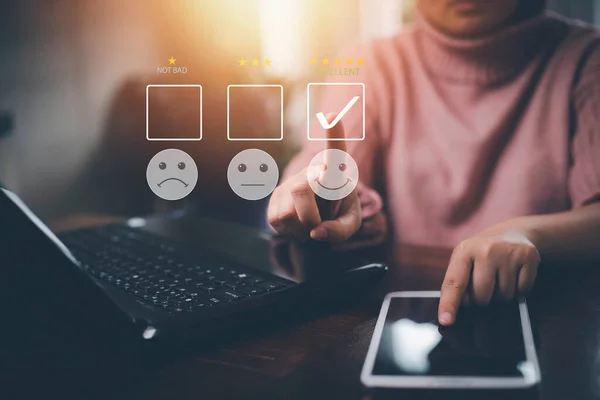 Happy and unhappy Smiley face concept Customer service evaluation concept. smiling Asian female Is using a smartphone, woman is pressing face emoticon smiling in satisfaction on virtual touch screen.