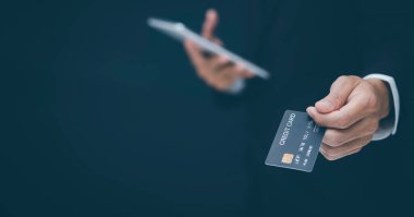 İş adamı, pazar stoklarının ok grafiğiyle birlikte Model kredi kartını tutuyor ve cep telefonu kullanıyor. Çevrimiçi alışveriş konsepti, bankacılık ve online alışveriş. Kapatın. Boşluğu kopyala, 