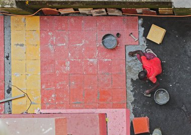 04 10 2021 Adam, Lokgram Kalyan Maharashtra Hindistan 'ın zemininde kırmızı ve sarı fayansları tamir ediyor.