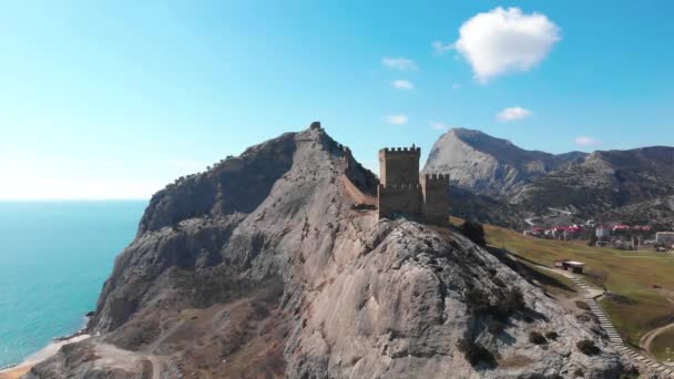 Pintoresca antigua torre fortaleza medieval genovesa y pared de piedra en la colina cerca del mar en soleado día de primavera. Avión no tripulado que se desliza a la pared de fortificación en la montaña hermosa en Crimea — Vídeos de Stock