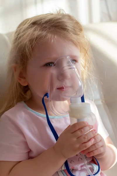 Little girl having inhalation for easing cough. Caucasian blonde girl inhales couples containing medication to stop coughing. — Stock Photo, Image