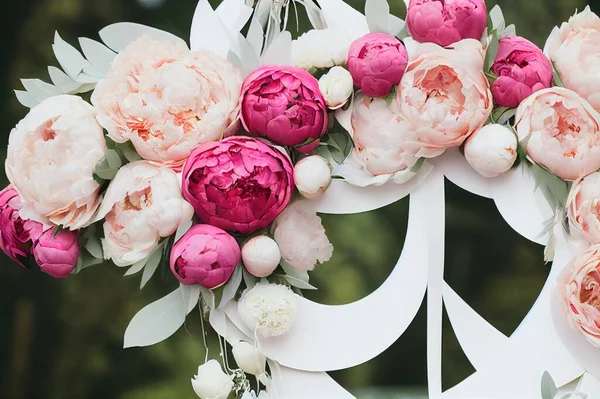 The concept of wedding decor, street decoration, wedding arch is decorated with flowers pink and white peonies. Wedding day, ceremony place for the bride and groom, decor, flowers, florists.