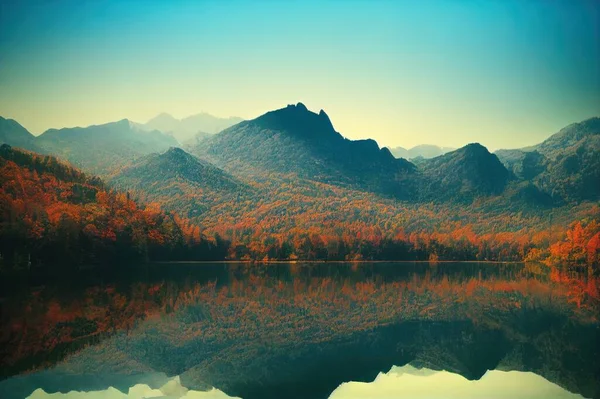 Mountain lake with autumn reflection of trees. Autumn mountain lake landscape. Lake i autumn mountains. Autumn mountain lake view