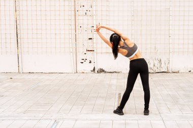 Güzel, koyu renk saçlı atlet kadın dışarıda kas germe hareketleri yapıyor. Dolu hayat kavramı, doğal ve sağlıklı hayat. Kadın sporları.