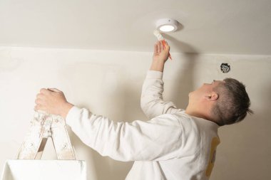 Tavanın detaylarını boyamak için fırça kullanan genç bir erkek ressam. özel iş, profesyonel iş kavramı.