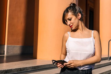 Çekici bir Latin kadının cep telefonundan gelen mesajları incelerken ve cevaplarken orta boy görüntüsü. Teknoloji, iletişim konsepti.