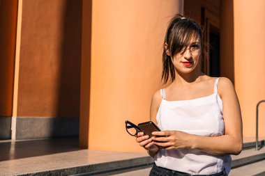 Çekici bir Latin kadının cep telefonundan gelen mesajları incelerken ve cevaplarken orta boy görüntüsü. Teknoloji, iletişim konsepti.