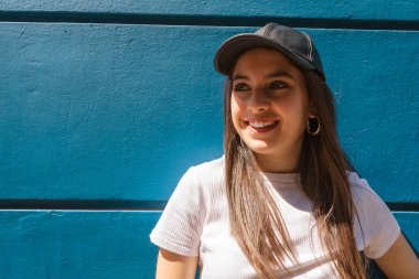 Kısa mesaj için gülümseyen ve mavi arka planı olan genç bir İspanyol kadının portresi. Boşluğu kopyala.