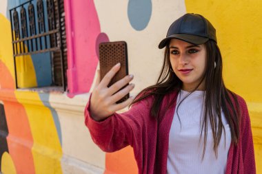 Genç milenyum kadını akıllı telefonuyla sokakta selfie çekiyor..