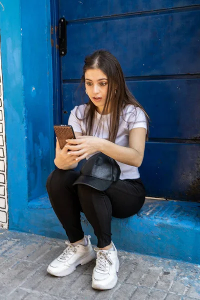 Retrato Una Hermosa Adolescente Revisando Mensajes Teléfono Celular Sentado Puerta —  Fotos de Stock