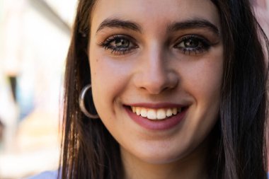 Geniş tebessümlü, gri gözlü Latin bir kızın aşırı yakın çekimi..