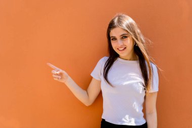 Havalı, sevimli, sevimli, çekici, çekici, çekici, çekici, çekici, çekici, güzel esmer kız portresi. Sıradan kot gömlekli, düz saçlı, fotokopi odası, turuncu arka planda izole edilmiş.