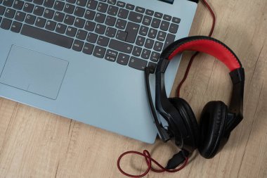 Bir dizüstü bilgisayar ve çalışma masasında mikrofon ya da kulaklık olan bir çift kulaklık. Teknoloji, iletişim, ana ofis kavramı