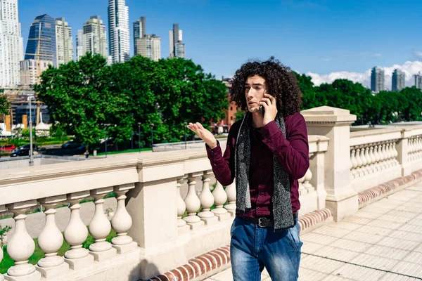 Egy Fiatal Göndör Hajú Latin Férfi Portréja Aki Telefonon Beszél — Stock Fotó