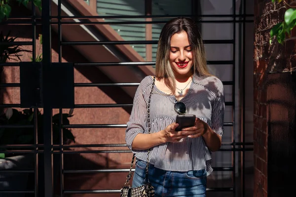 Retrato Una Hermosa Joven Revisando Mensajes Teléfono Celular Entrada Edificio —  Fotos de Stock