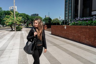 Güneşli bir günde şehirde yürüyen güzel bir Latin girişimcinin portresi..