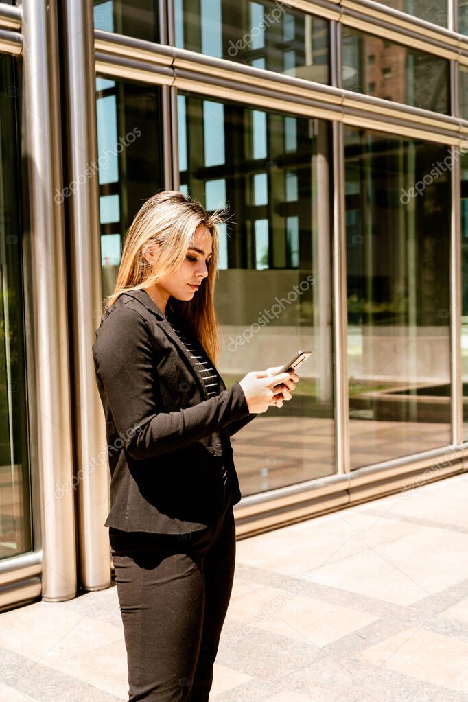 A Portrait in vertical orientation of a businesswoman consulting her phone.