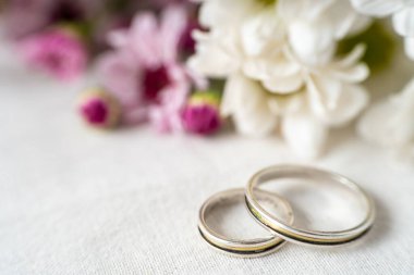 Güzel menekşe, beyaz çiçekler ve geniş bir fotokopi alanı olan bir çift evlilik ya da nişan yüzüğünün yakın çekimi. Aşk konsepti.