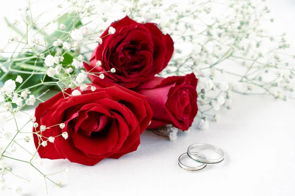 Пара Обручок Білій Поверхні Красивими Квітучими Червоними Трояндами Маленькими Білими — стокове фото