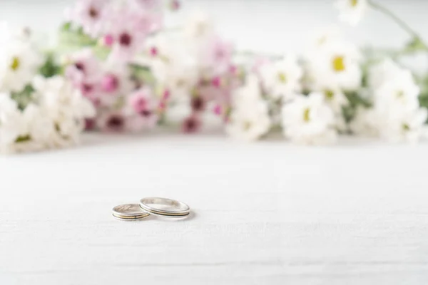 Весільні Кільця Білій Поверхні Красивими Білими Фіолетовими Квітами Фокусу Задньому — стокове фото